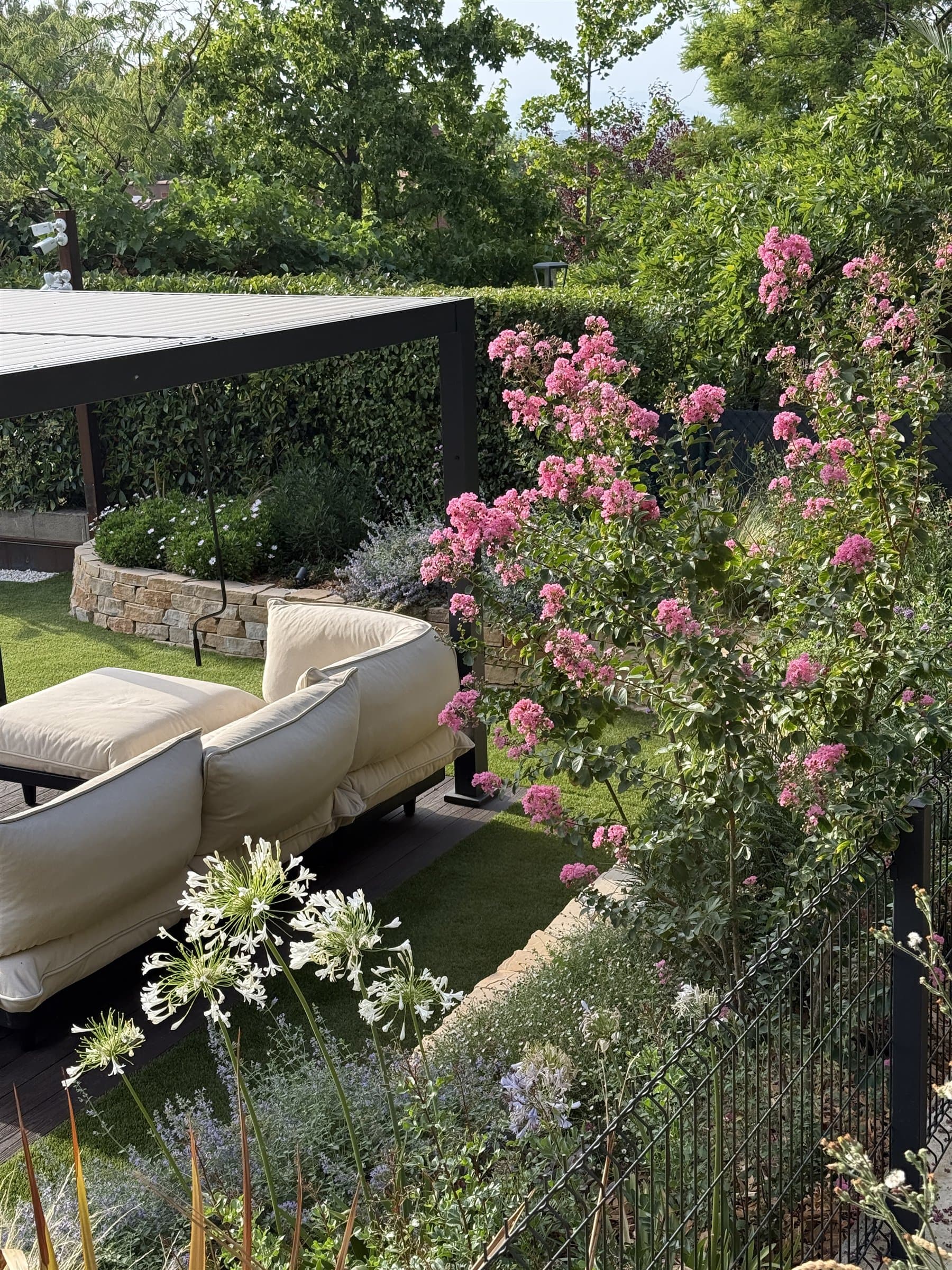 Zona de descans envoltada de lagerstroèmies florides i vegetació